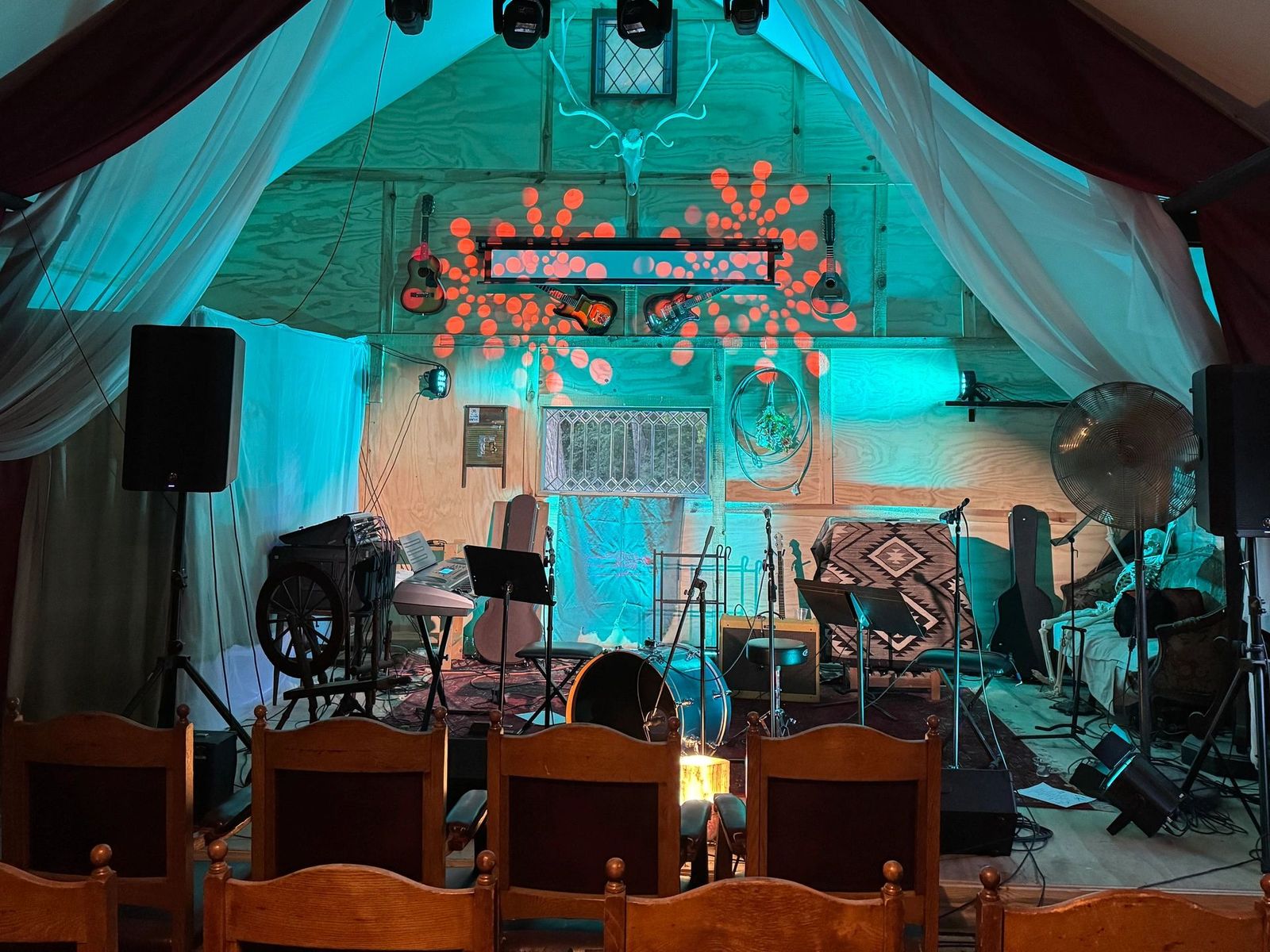 Rows of wooden chairs facing a lit stage in the barn