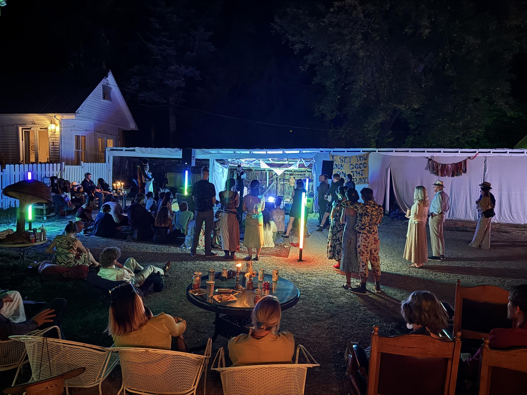 Evening reception crowd gathered around a candlelit table and draped tent
